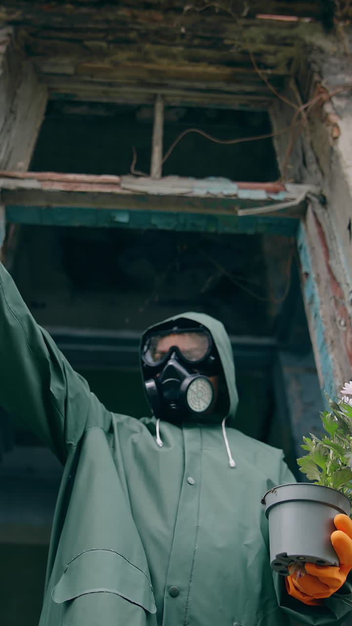 Ecological problems. Ecologist in protective gloves and suit pulling out fresh flowers from flower pot. Abandoned place. Biological attack. Vertical video