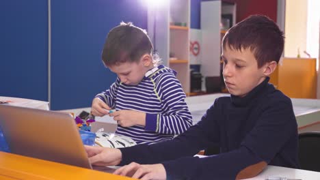 two boys building with robotics kit and laptop