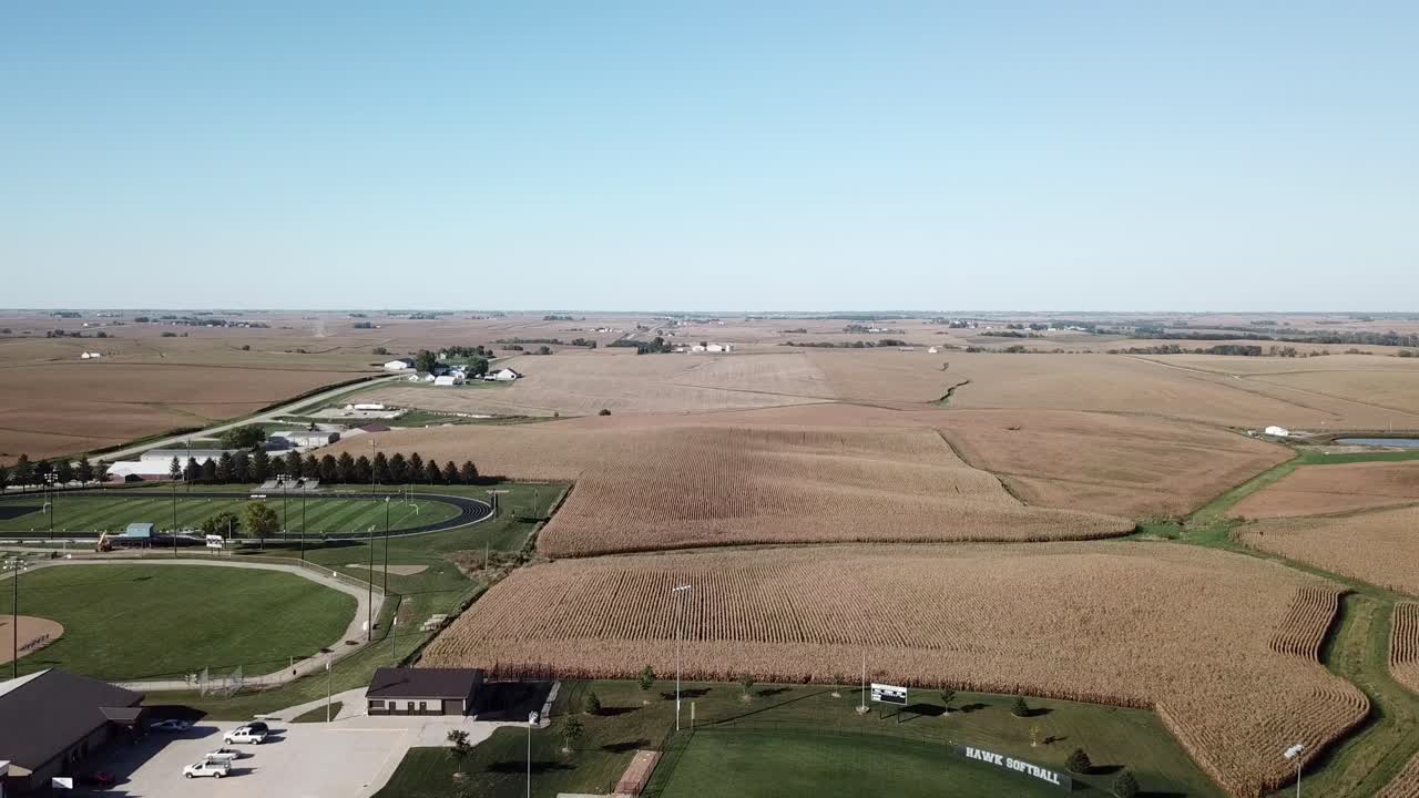 Aerial Drone Footage Of High School Football Field And Tall Brown Fields Ready For Harvest In Rural, Midwest Iowa Corn Country