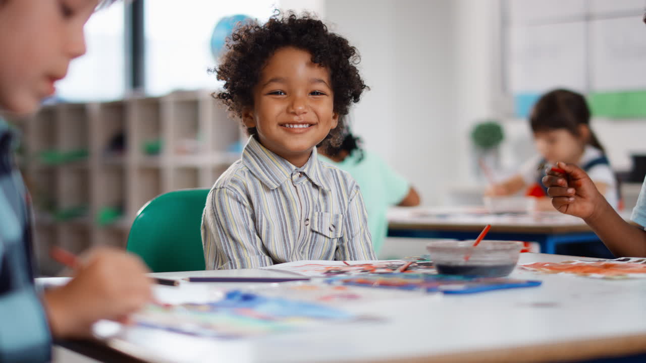 Portrait Of Smiling Male Elementary School Pupil Sitting In Classroom In Art Lesson