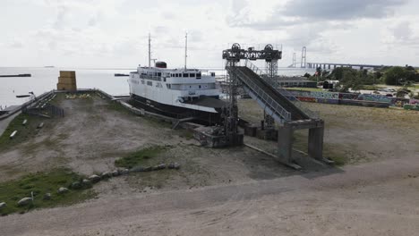 old boat in the harbor near a big bridge over the sea