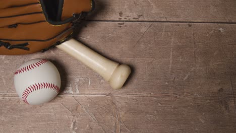 Overhead-Studio-Baseball-Still-Life-With-Wooden-Bat-And-Ball-In-Catchers-Mitt-On-Wooden-Floor