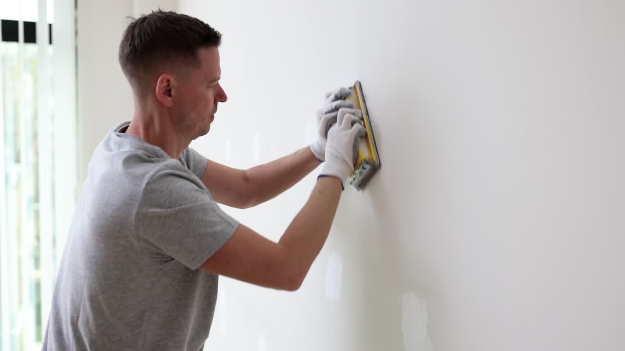 Man sanding a wall during home renovation