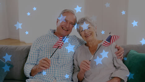 animación de estrellas azules brillantes sobre el retrato de una feliz pareja de mayores sosteniendo banderas estadounidenses
