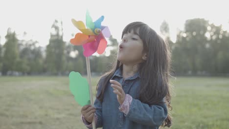 adorable chica latina soplando en abanico de papel al aire libre