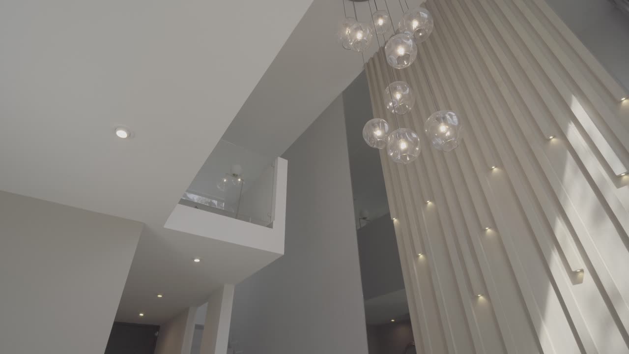 Slow establishing shot of chandeliers hanging with a glass overhang in a house