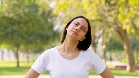 mujer india haciendo ejercicio de cuello en un parque por la mañana