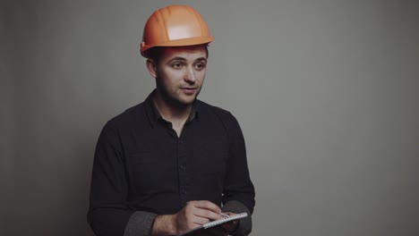 young man architect in building helmet. smiling young man architect in building helmet standing and writing on clipboard