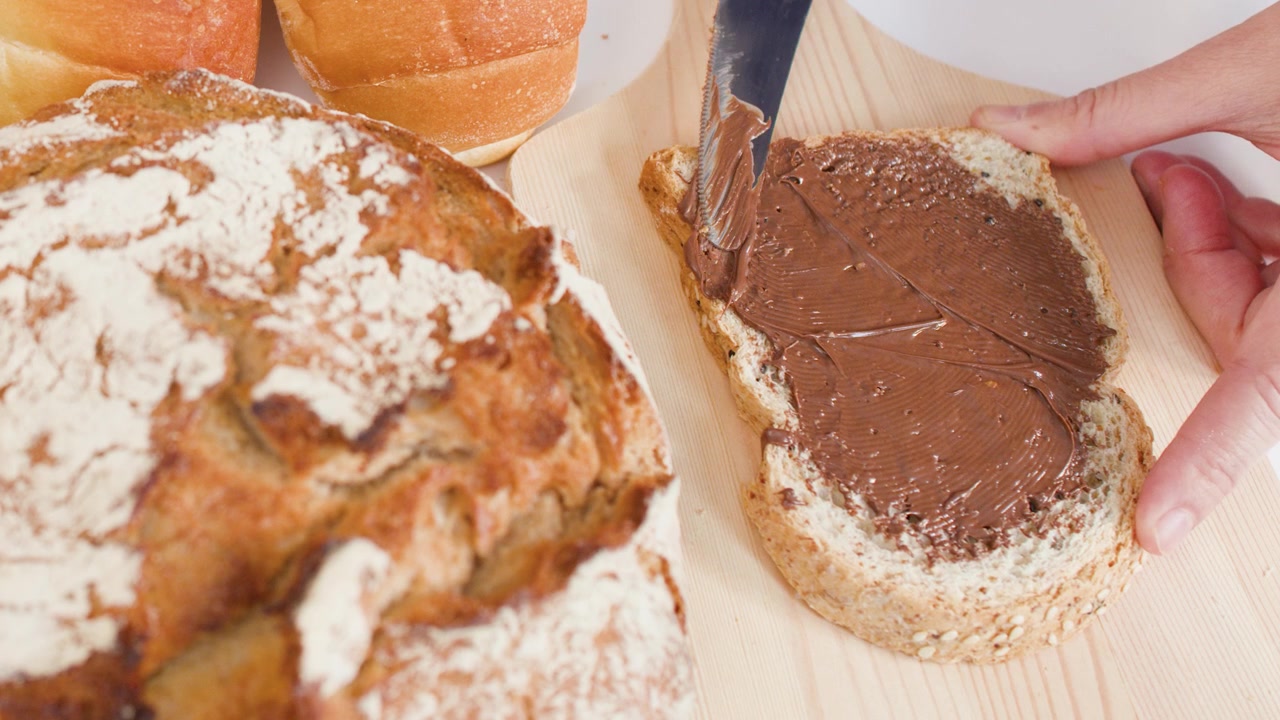 Spreading Chocolate Hazelnut Spread on a Slice of Whole Grain Bread