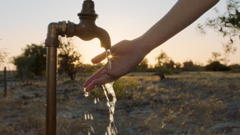 Mujer-Lavándose-Las-Manos-Bajo-El-Grifo-En-Una-Granja-Rural-Al-Atardecer-Agua-Dulce-Que-Fluye-Del-Grifo