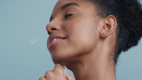 retrato de belleza de cerca hermosa mujer afroamericana tocando el rostro con plumas cayendo sobre la piel suave disfrutando del cuidado sensual de la piel acariciando suavemente la piel sana en cámara lenta