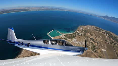 Pequeño-Avión-Volando-Sobre-La-Isla-Con-La-Montaña-De-La-Mesa-Y-El-Océano-Al-Fondo