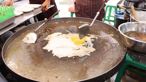 cooking an egg on a hot griddle outdoors.