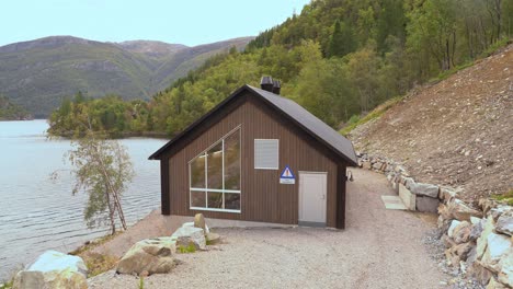 Markaani-hydroelectric-powerplant-is-producing-electricity-from-freshwater-in-Vaksdal-Norway---Approaching-building-exterior-with-glimpse-of-pelton-turbine-inside---Bolstadfjorden-fjord-to-the-left
