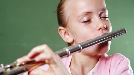 schoolgirl playing flute in classroom at school