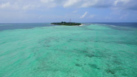 drone flying over turquoise seawater towards dhangeti tropical and local island, maldives