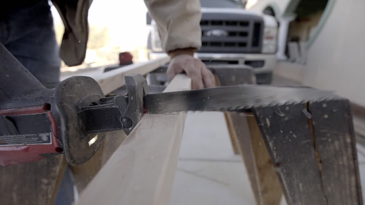 Closeup of electric straight blade saw cutting into wood plank, slow motion