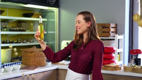 Female-staff-arranging-olives,-preserves-and-olive-oil-on-counter