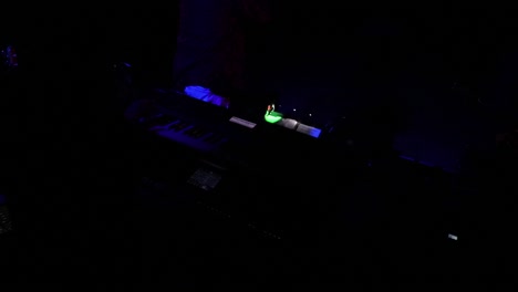 organ musician in the dark with the lights flashing live on concert backstage behind the band