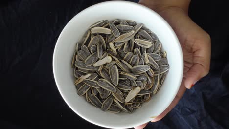 close-up of a bowl of sunflower seeds held in hands