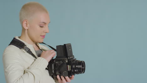 vista laterale del fotografo femminile che utilizza una fotocamera a pellicola di medio formato 02