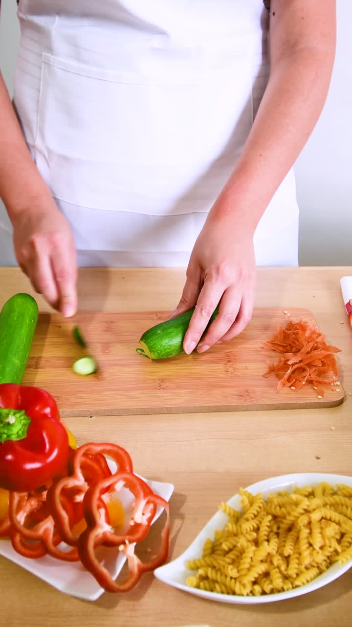 Close up hands cutting cucumber , preparing for a healthy organic vegetarian meal with peppers.
