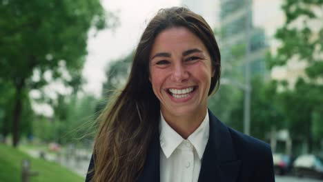 tomada cinematográfica de una joven feliz mujer de negocios sonriendo en la cámara satisfecha con su día de trabajo en el parque de la ciudad por el camino a casa. concepto de empresa, éxito, negocios y finanzas, carrera femenina.