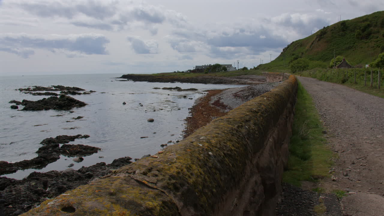 Wide shot looking South from Gourdon of local road with old sea wall
