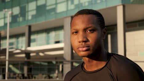 portrait of handsome african american male athlete in sportswear resting on a sunny afternoon. close-up. young black man looking at camera outdoors.