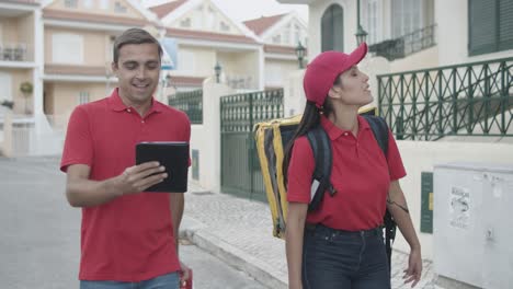 two happy couriers in red uniforms walking outside