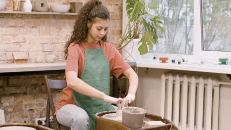 mujer empleada modelando una pieza de cerámica en una rueda de alfarero en un taller 2