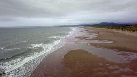 ariel view of harlech beach wales with vast sands crashing waves and a stormy sky