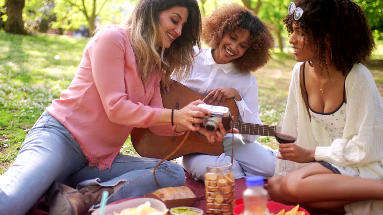Women enjoying a picnic with music and photography in the park