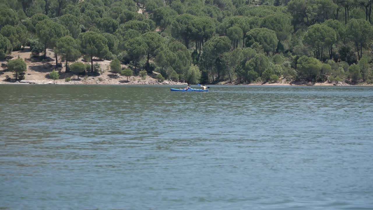 Two people on separete blue kayak paddling on lake pantano de San Juan, Madrid