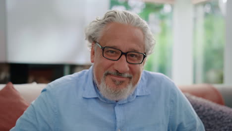 senior man smiling at camera. portrait of mature man sitting on couch in room