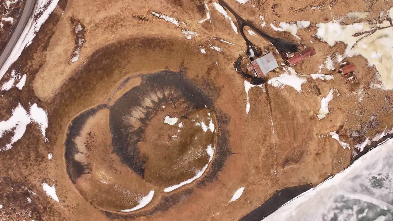 Top-down drone view of a volcanic pseudocrater along Lake Mývatn’s icy edge near Skútustaðir. Iceland