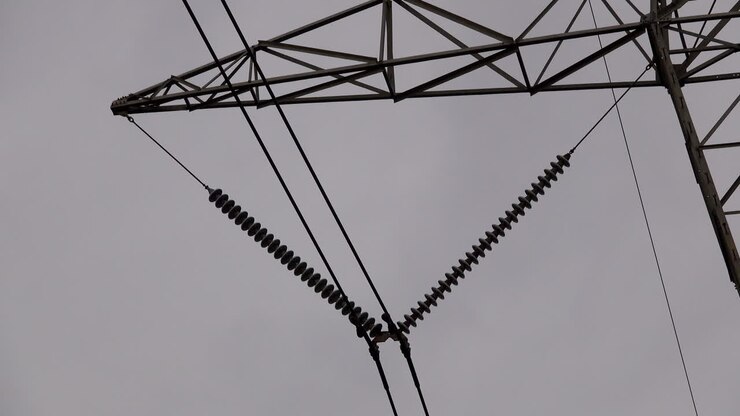 Close-up of electrical insulators and transmission lines on electrical pylon