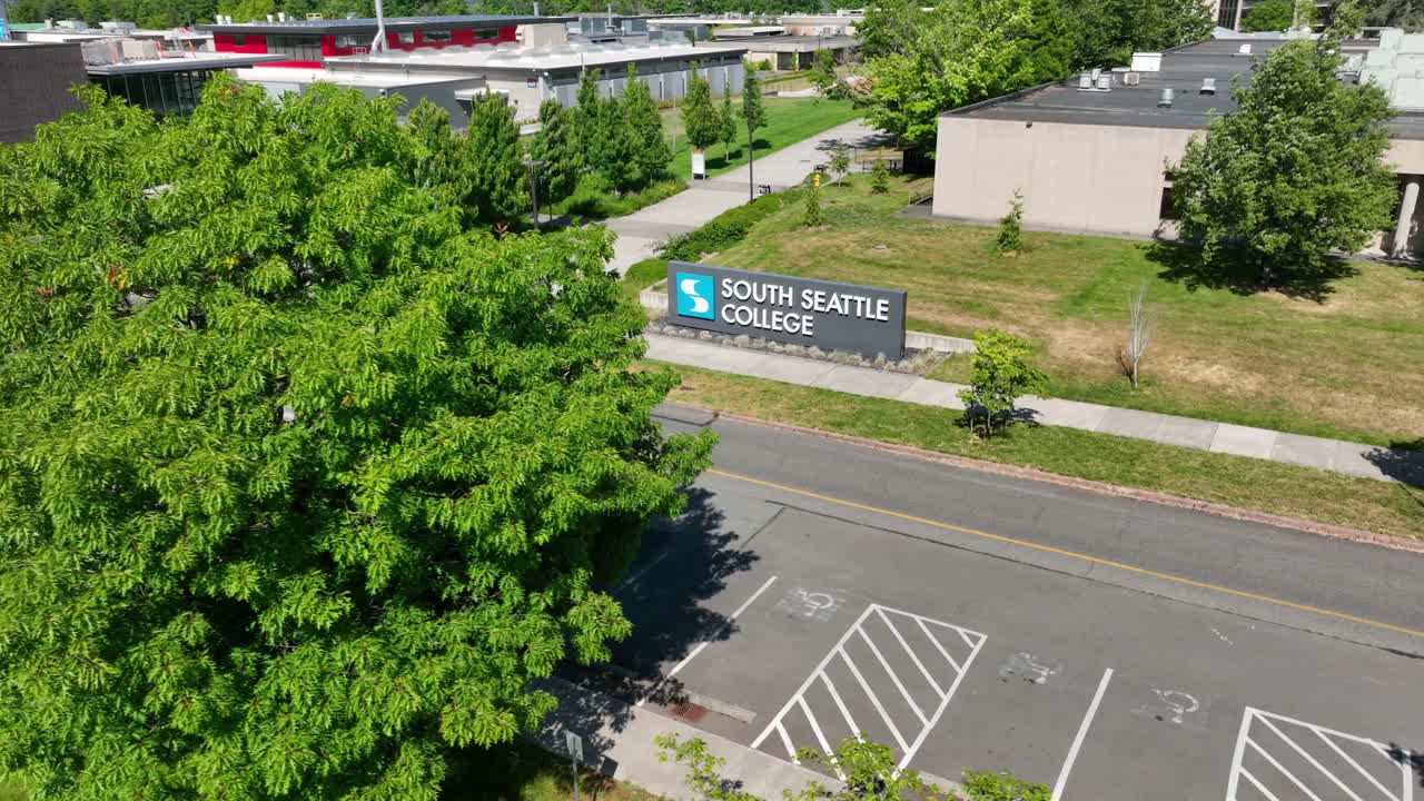 나무 뒤에서 나타나는 사우스 시애틀 대학 입구 표지판의 공개  ⁇