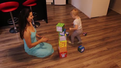 mother playing with her little daughter building blocks and demolishing them