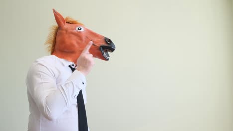 an office worker in a horse mask points his finger straight an office worker in a horse mask points his finger straight filming in the studio a place for advertising