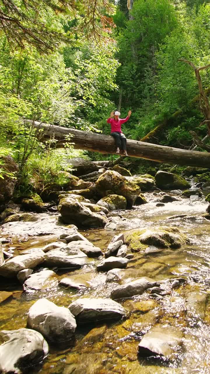 Person Sitting on Fallen Log Across a Stream in a Forest