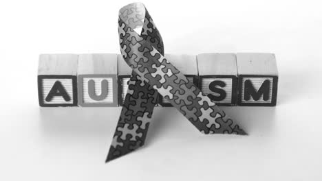 awareness ribbon falling in front of autism letter blocks in black and white