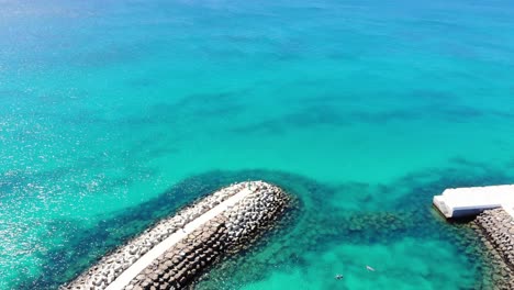 aerial view of idyllic blue ocean waters with breakwater wall surrounding bikini beach club at cape verde