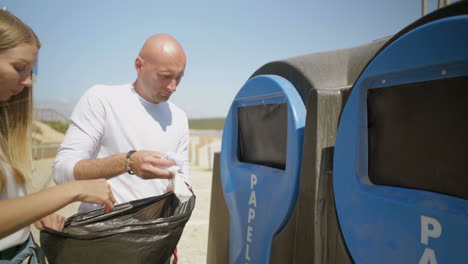 couple putting paper trash in container