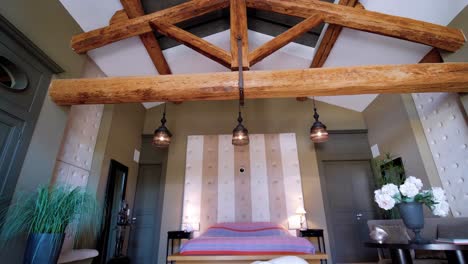 View-of-the-ceiling-and-the-immense-wooden-beams,-returning-horizontally-and-discovering-a-spacious-bedroom-and-its-bear-statue