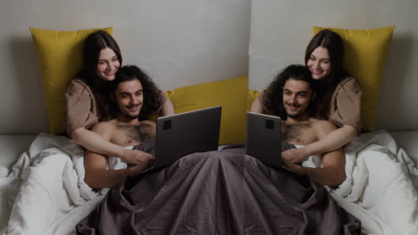 pareja en la cama con una computadora portátil
