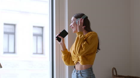 young woman singing and listening to music at home