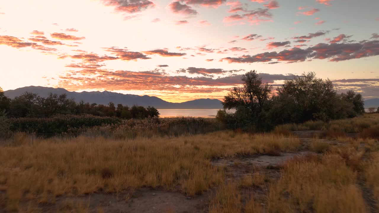 Pullback Aerial Of Utah Lake During A Vibrant Sunrise Revealing Jordan River Parkway Trail Nature Path, USA