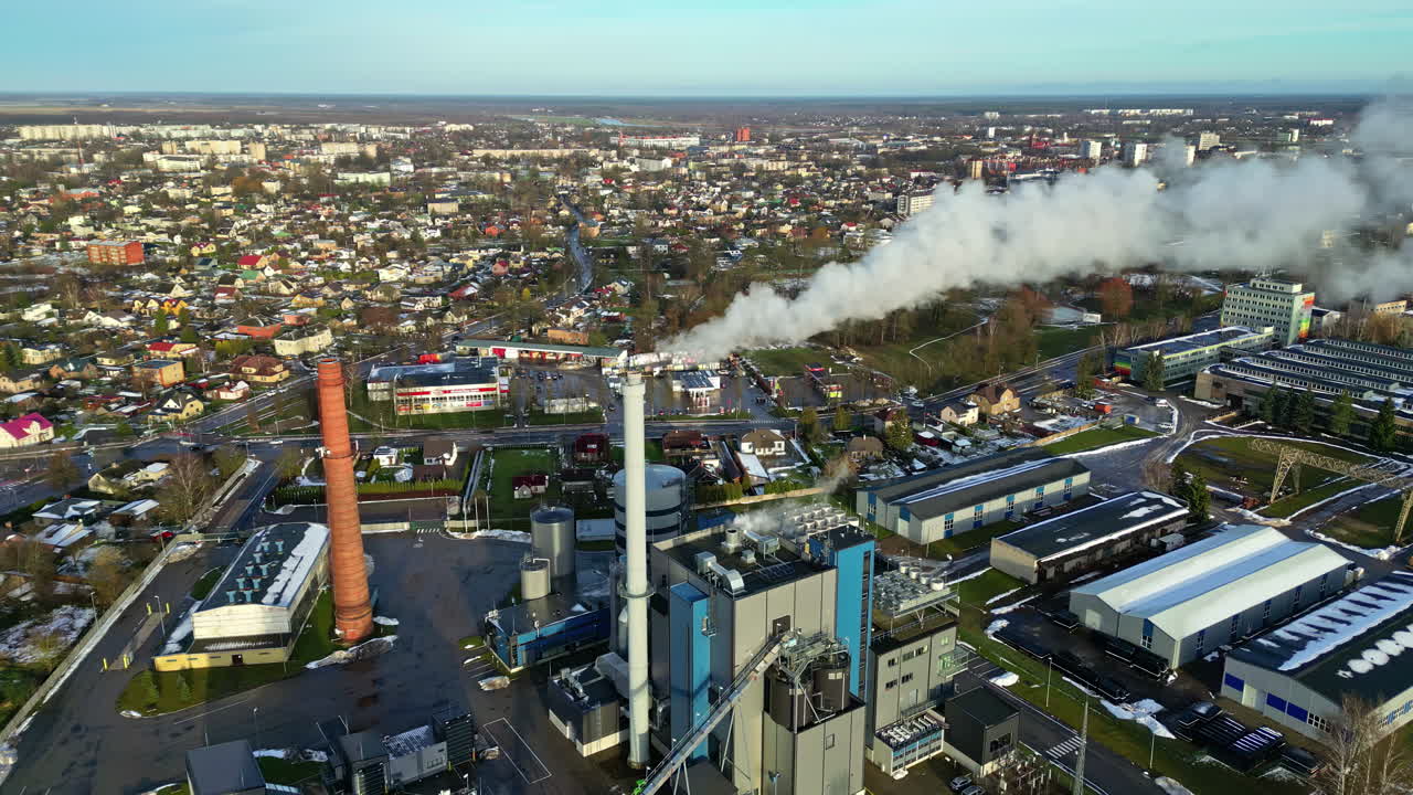 Et luftfoto af et bylandskab og et industriområde med røg fra skorstenen