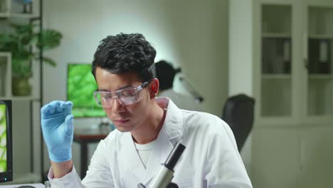 asian scientist man looking at test sample of leaf analyzing for biological experiment with organic plants. biologist specialist discovering organic gmo plants while working in